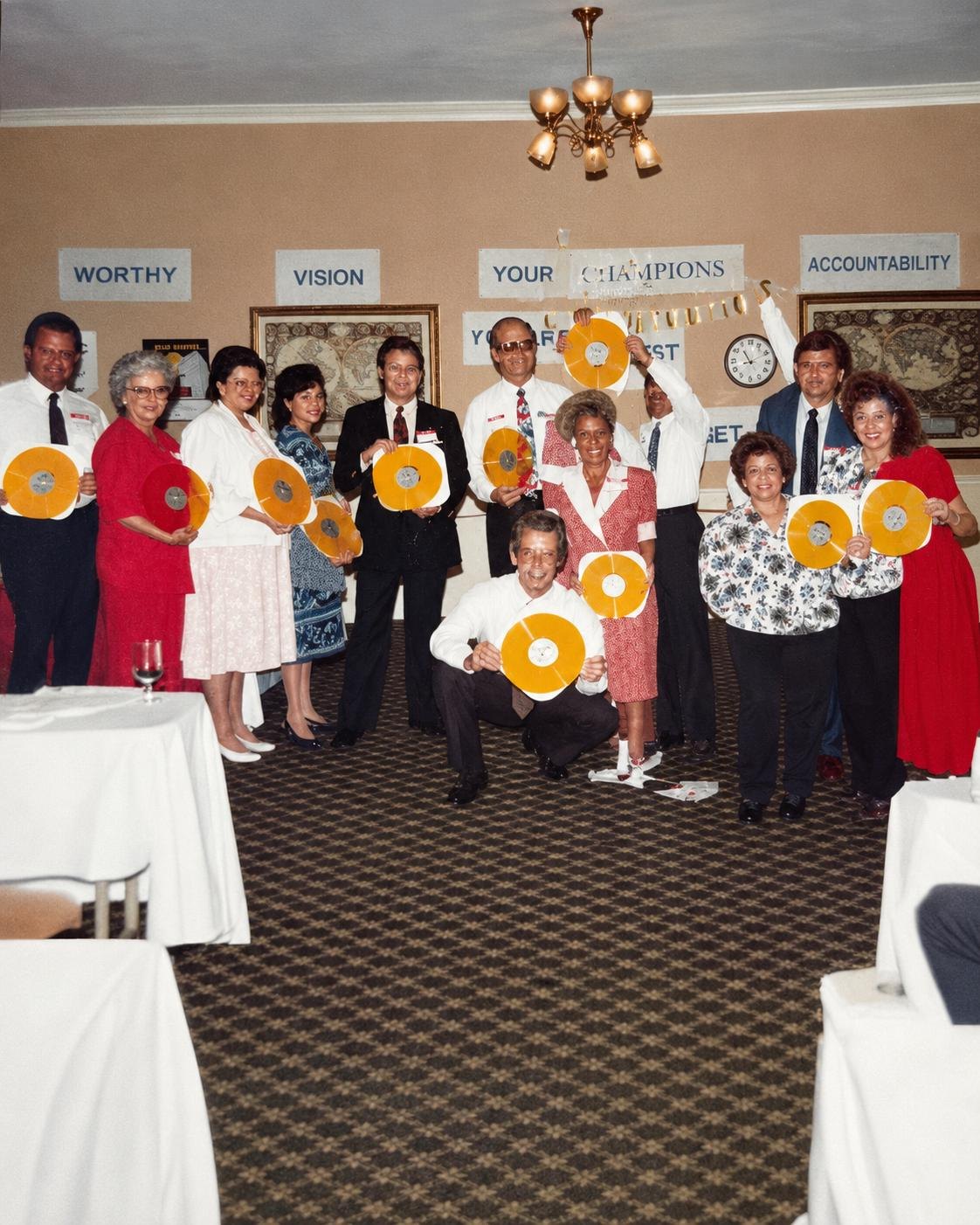 Charles Ernest Bailey and his award-winning Aflac team holding their gold records under a Your Champions banner
